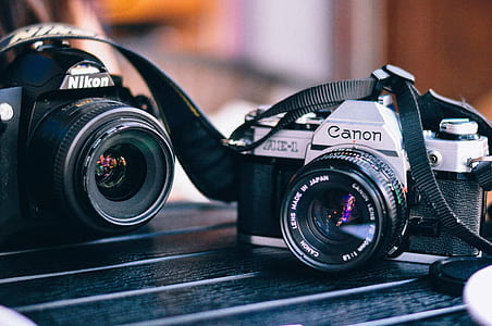 gray and black Canon camera beside black Nikon camera thumbnail