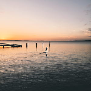 silhouette photography of person standing on boat thumbnail