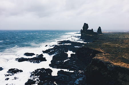 ocean water near black rock formation under clear sky during daytime thumbnail