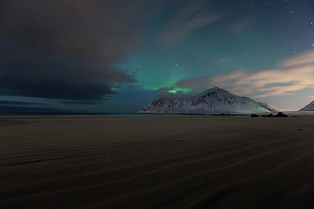 snow-covered mountain under green aurora borealis during nighttime thumbnail
