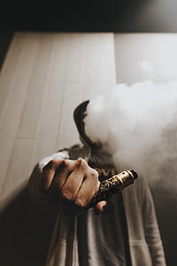 person holding gold and black pen-type vape thumbnail