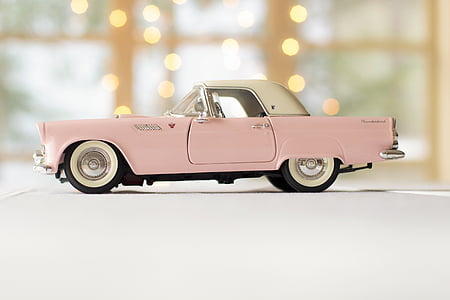 person taking photo of pink and white convertible coupe die-cast model thumbnail