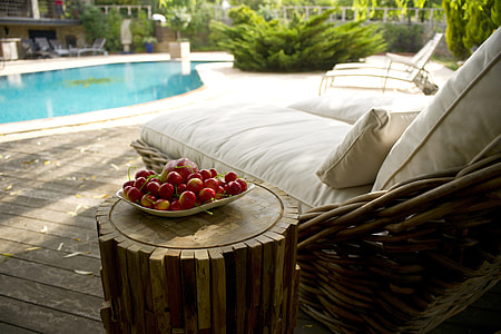 white fabric side pool lounge beside plate of fruits beside pool during daytime thumbnail