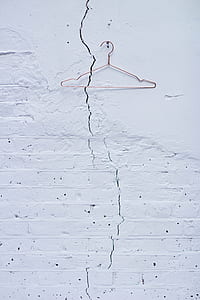 metal clothes hanger hanged against concrete wall thumbnail