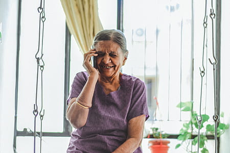 woman holding white talking to the phone beside window thumbnail