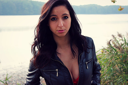 woman in black leather zip-up jacket near the body of water photo in daytime thumbnail