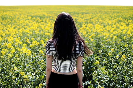 woman wearing white and black striped t-shirt surrounded by yellow petaled flower at daytime thumbnail