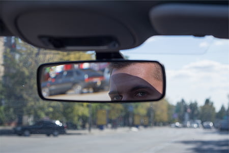 reflection of man face on vehicle rear view mirror thumbnail