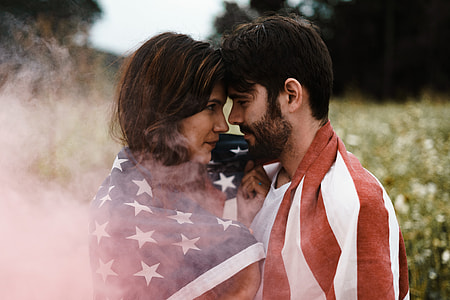 selective photography of man and woman face to face covered with U.S.A. flag thumbnail