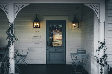 gray wooden door between two black lighted sconces in balcony thumbnail