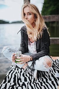Blonde woman having a healthy snack at the wooden pier thumbnail