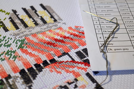 grey needle on white paper beside cross stitch thumbnail