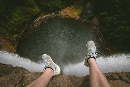 person sitting on cliff near waterfalls thumbnail