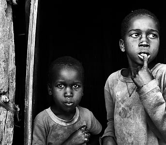 grayscale photography of boy biting his finger thumbnail