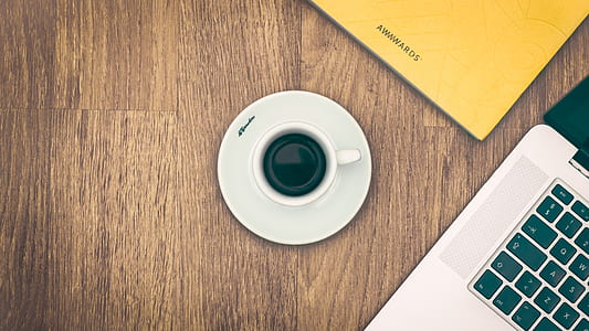white ceramic teacup beside laptop thumbnail