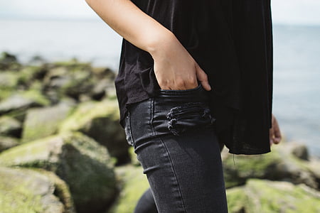 person in black shirt putting his right hand in pocket near on body of water thumbnail
