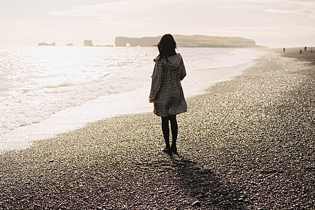 woman standing on sand near ocean during daytime thumbnail