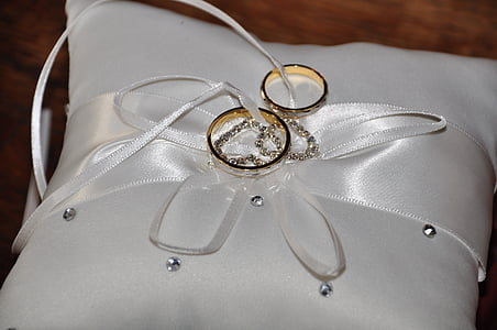 two gold-colored rings on top of white throw pillow thumbnail