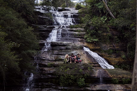 three person on cliff of waterfalls thumbnail