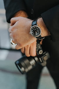 person holding black DSLR camera with watch thumbnail