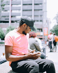 Man Sitting on Gray Bench While Using Mobile Phone thumbnail
