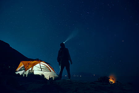 man using headlamp beside cabin tent thumbnail