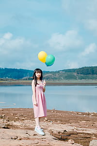 Woman Holding Balloons Standing on Beige Sand thumbnail