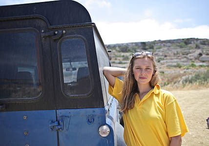 Young Woman Wearing Half-Sleeved Yellow Shirt Posing Besides SUV thumbnail