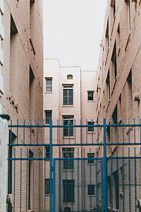 brown concrete building with blue gate under white sky thumbnail