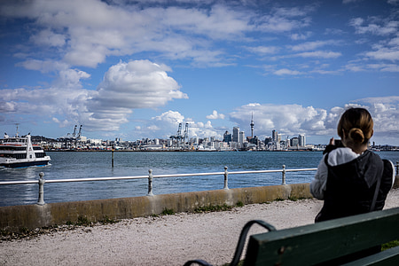 woman sitting on bench facing body of water thumbnail