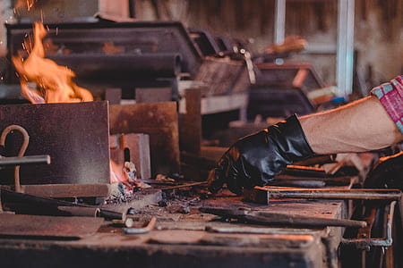 person wearing black leather glove while holding metal into fire thumbnail