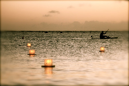 selective silhouette phtography of candles on body of water thumbnail
