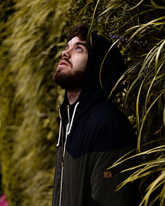 man in black and gray hoodie beside hedge thumbnail