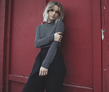 woman in gray and black striped long-sleeved shirt behind brown wooden wall thumbnail