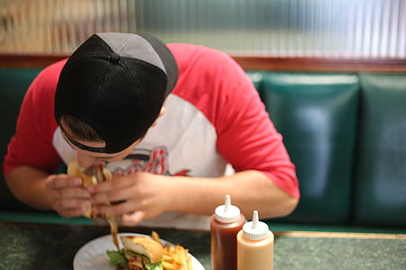 man eating burger while sitting on sofa thumbnail
