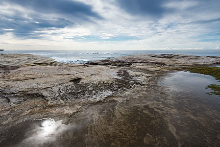 body of water with rocks under blue cloudy skies thumbnail