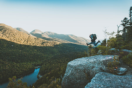 man jumping above rock formation near body of water thumbnail