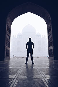 silhouette photography of man standing front of temple thumbnail