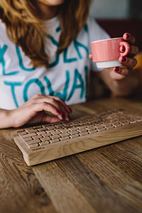 Closeup of female hands typing text on a wireless wooden keyboard thumbnail