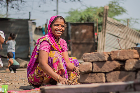 smiling woman sitting near stacked concrete bricks during daytime thumbnail