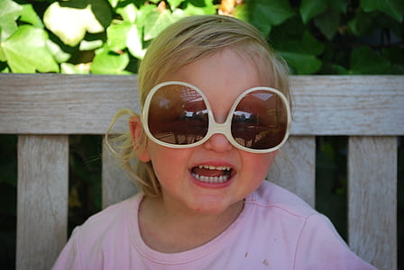 toddler girl wearing oversize sunglasses sitting on bench thumbnail