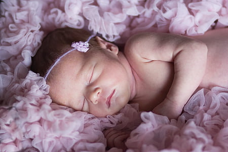 baby lying on pink rosette cushion thumbnail