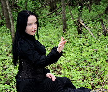 woman in black long-sleeved long dress sitting on a trunk thumbnail
