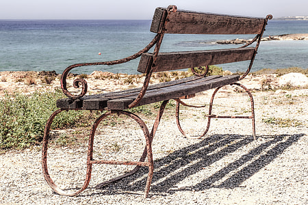 brown metal framed outdoor bench near body of water thumbnail