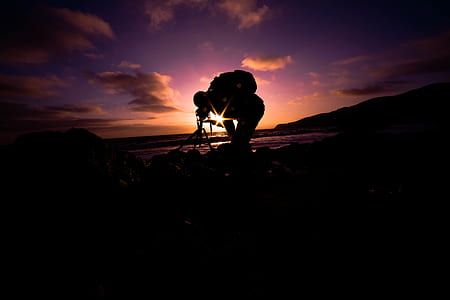 human taking photo near sea during golden hour thumbnail