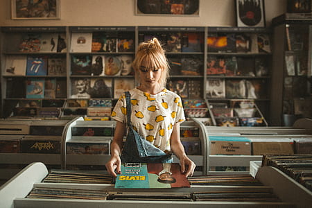 woman standing in front of rack while holding Elvis vinyl sleeve inside store thumbnail