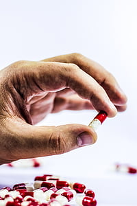 person holding red and white medication capsule thumbnail