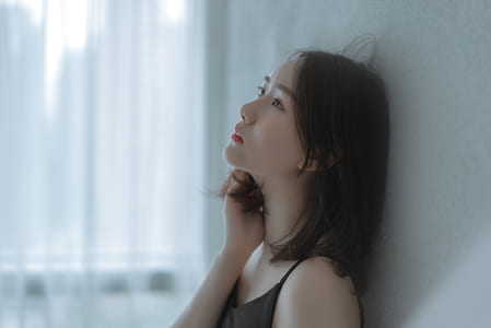 woman leaning on white wall near window thumbnail
