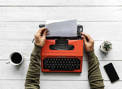 person pulling printer paper on orange typewriter thumbnail