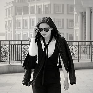 Greyscale Photo of Woman Wearing Sunglasses Long Sleeves Shirt and Skirt during Daytime thumbnail